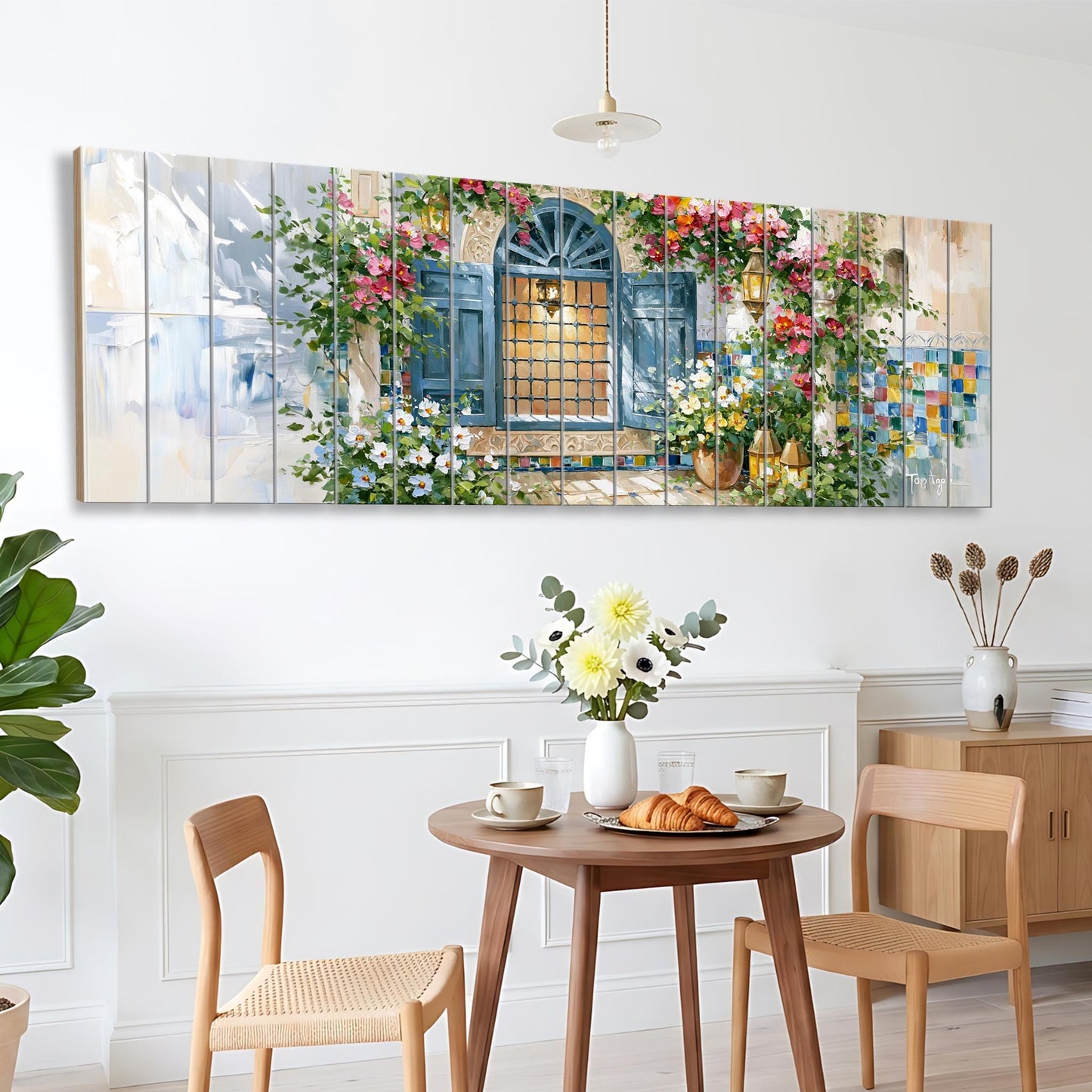 a dining area with a table set for two, featuring a vase of flowers, a plate of pastries, and two chairs. Above the table, there is a large painting depicting a window with a flower-filled sill.