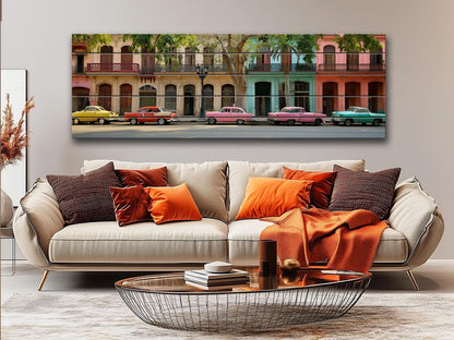 a large, colorful painting of a street scene with vintage cars parked along the road, displayed on a wall above a beige sofa with orange and brown throw pillows.