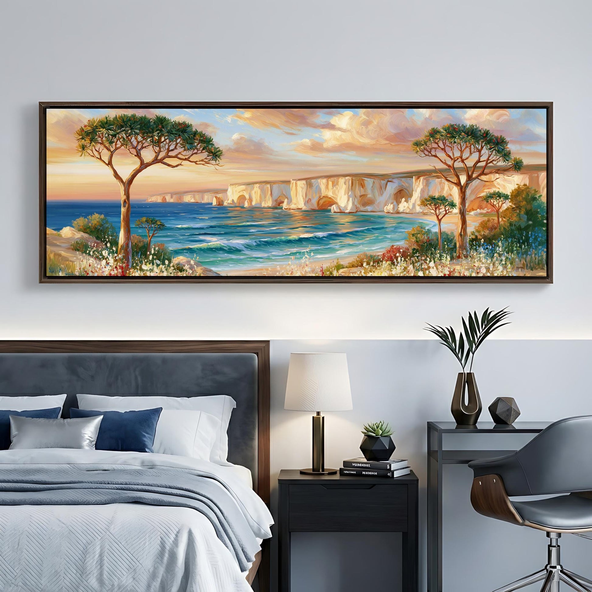 a large painting of a serene landscape with a beach, cliffs, and trees, hanging on a wall above a bed with a gray headboard.