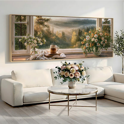 a large painting of a scenic landscape with a coffee cup and flowers on a windowsill, set against a white wall. The painting is framed and hangs above a white sofa and a round coffee table in a cozy living room setting.