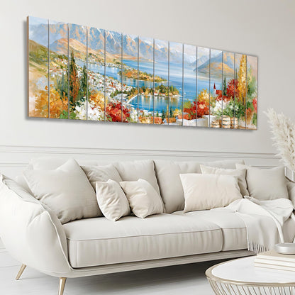 a large, colorful painting of a scenic landscape with mountains, a lake, and a town, hanging on a wall above a white sofa in a living room.