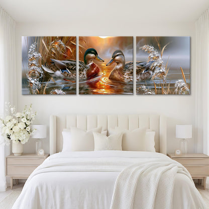 A large, three-panel painting depicting ducks swimming in a body of water, with a warm, golden sunset in the background.