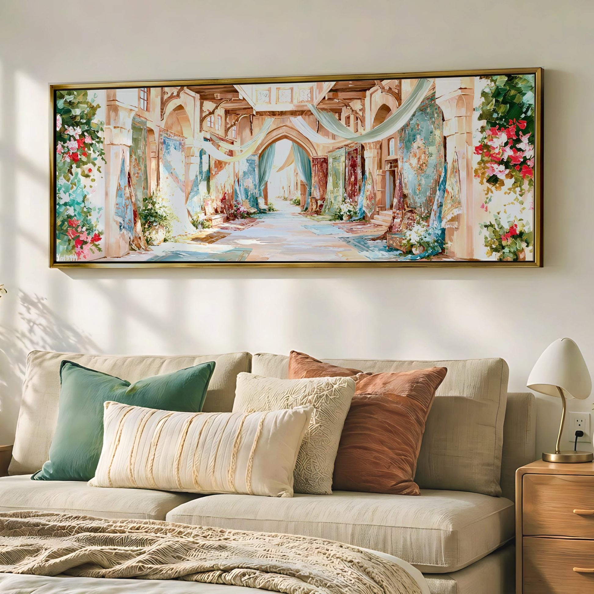 a large, colorful painting of a hallway or corridor hanging on a wall above a beige couch with various pillows.