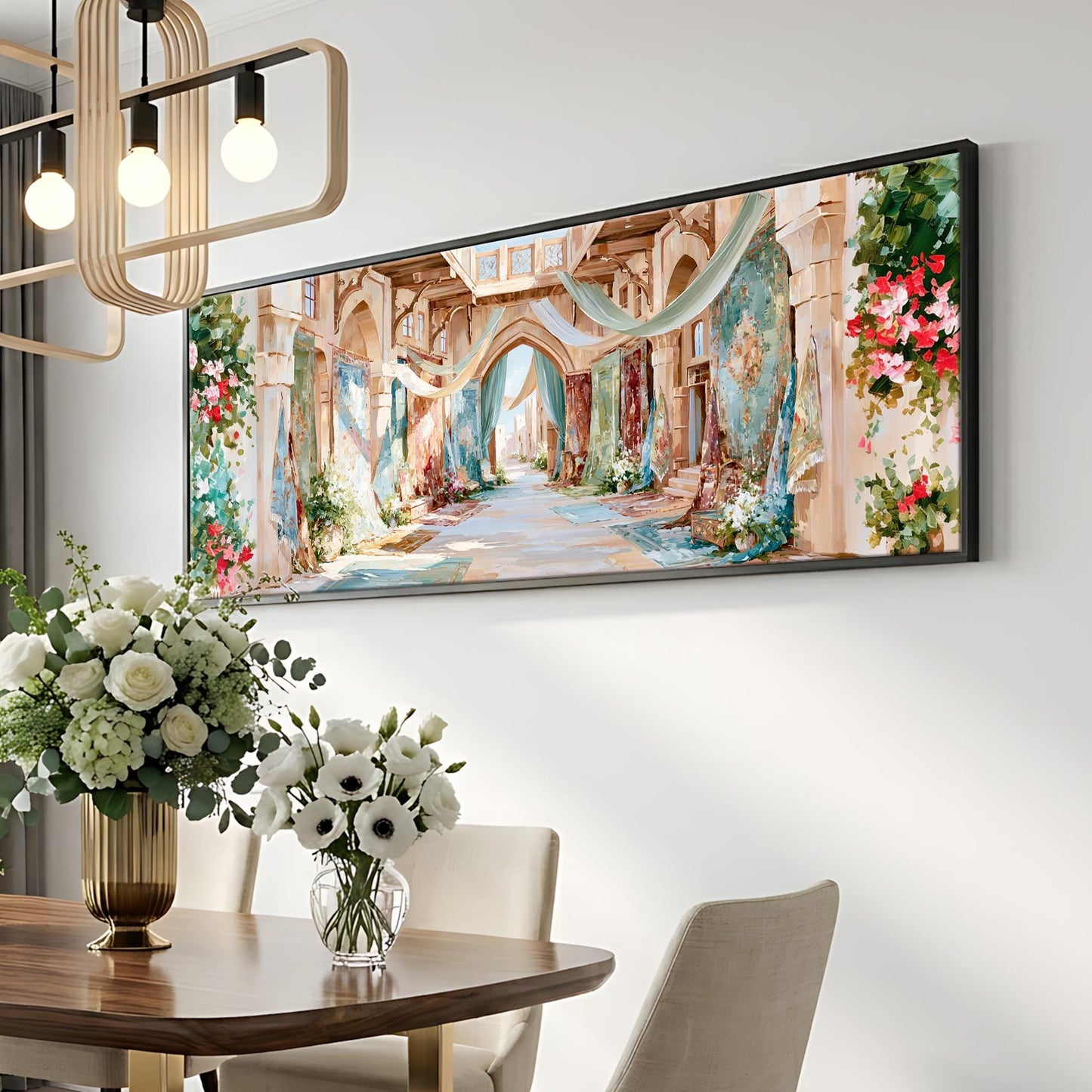 a large, colorful painting of an ornate, historic-looking building with arches and columns, hanging on a wall above a dining table with a vase of white flowers.
