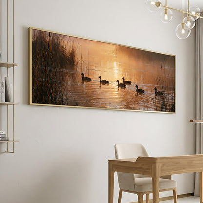 a large framed painting of ducks swimming on a lake, with a warm sunset in the background.