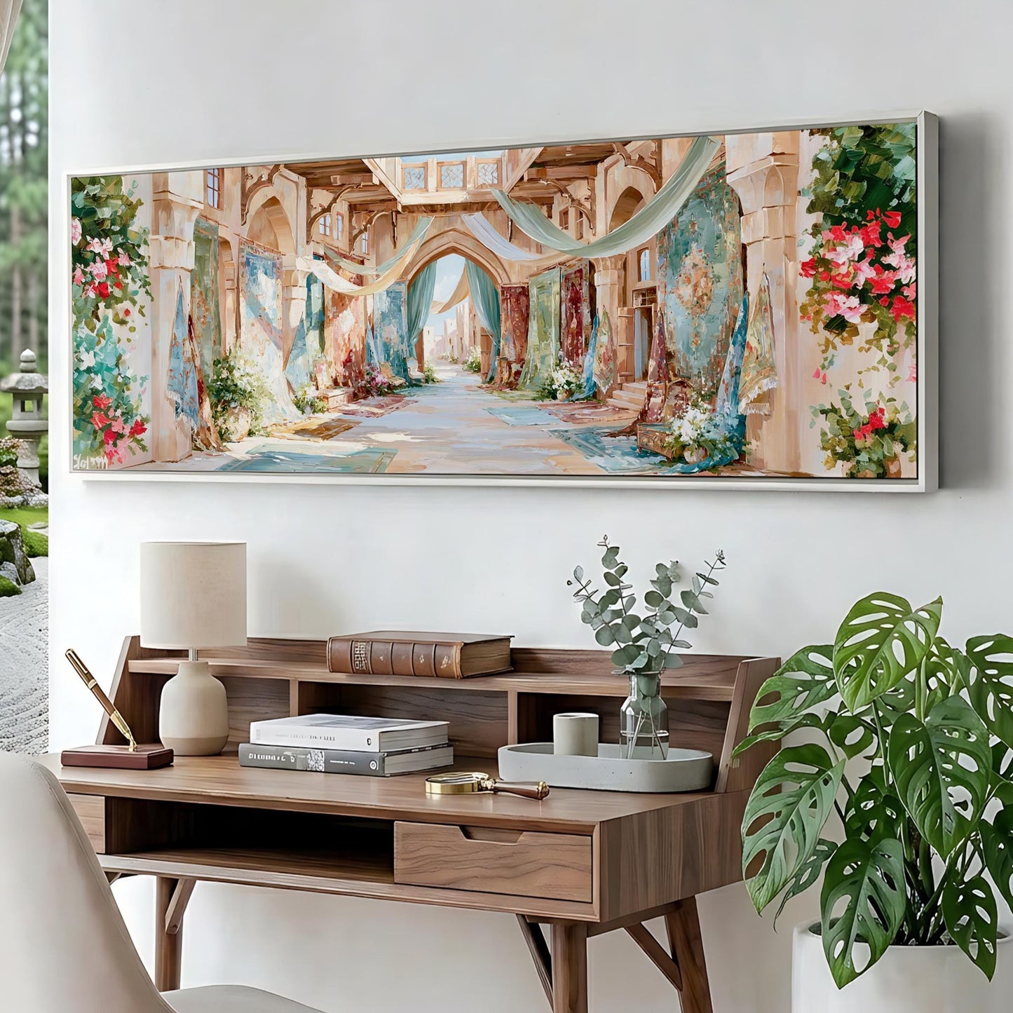 a large painting of an ornate, colorful hallway with arches and floral decorations hanging on a wall above a wooden desk with a lamp and various decorative items.