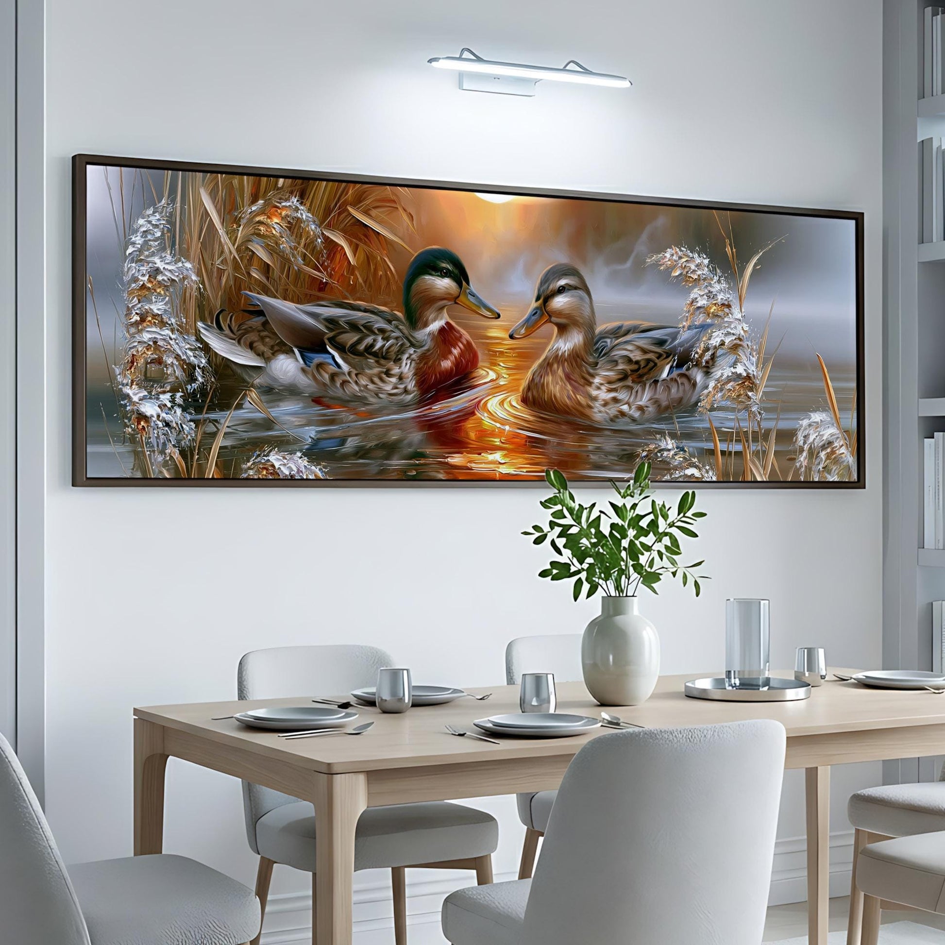 a large painting of ducks swimming in a pond, hanging on a white wall above a wooden dining table.