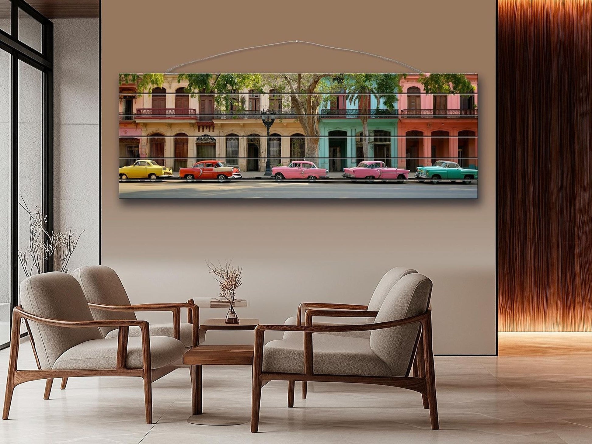 a large, colorful painting of a street scene with vintage cars parked along the road. The painting is hung on a wall above a seating area with two chairs and a small table.