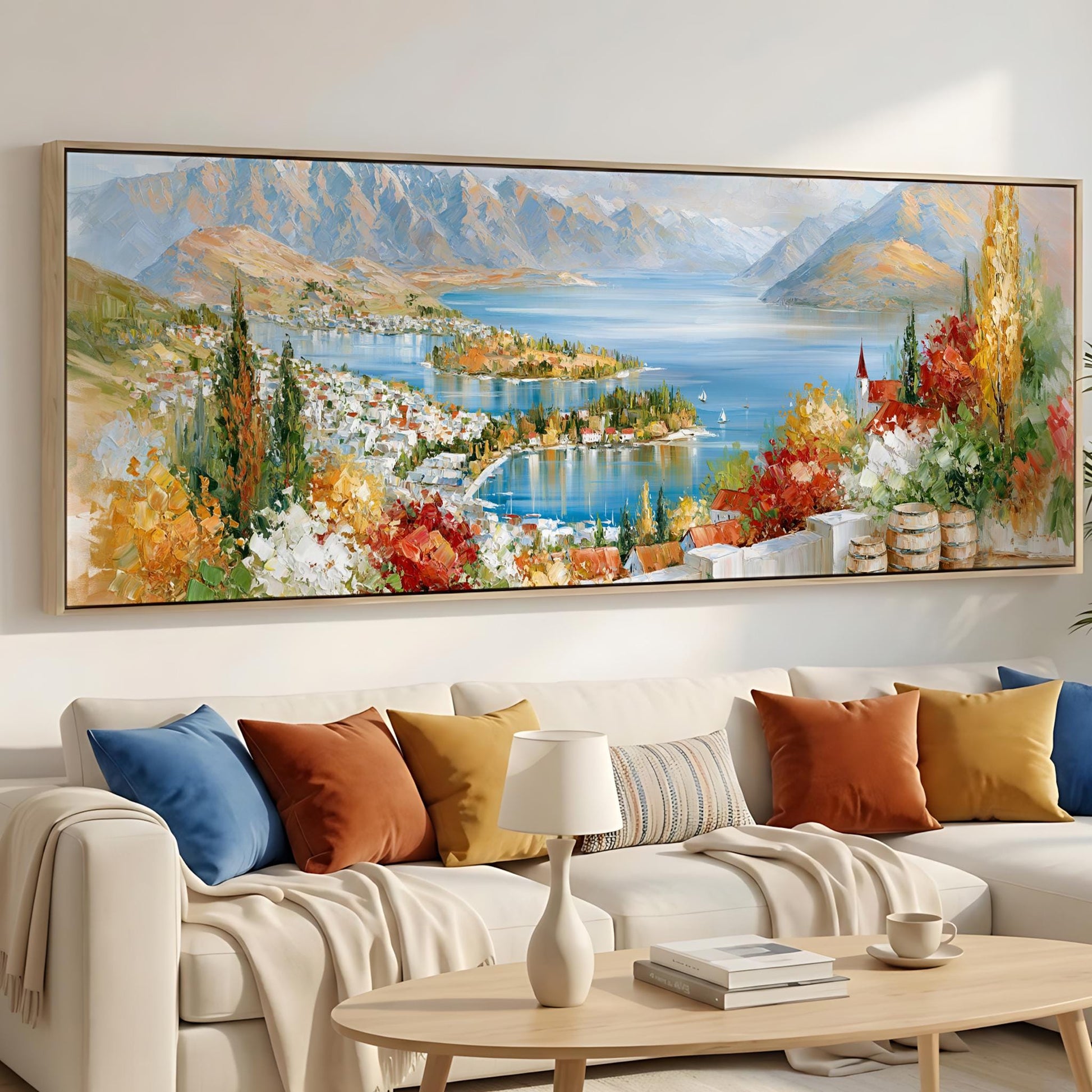 a large, colorful painting of a scenic landscape hanging on a wall above a white couch with various pillows.