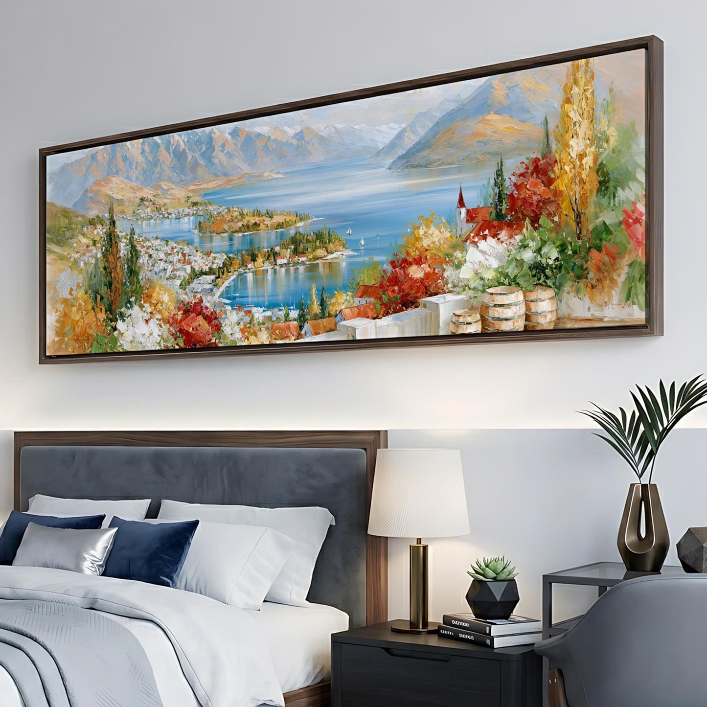 a large painting of a scenic landscape hanging on a wall above a bed with white bedding and a nightstand with a lamp.