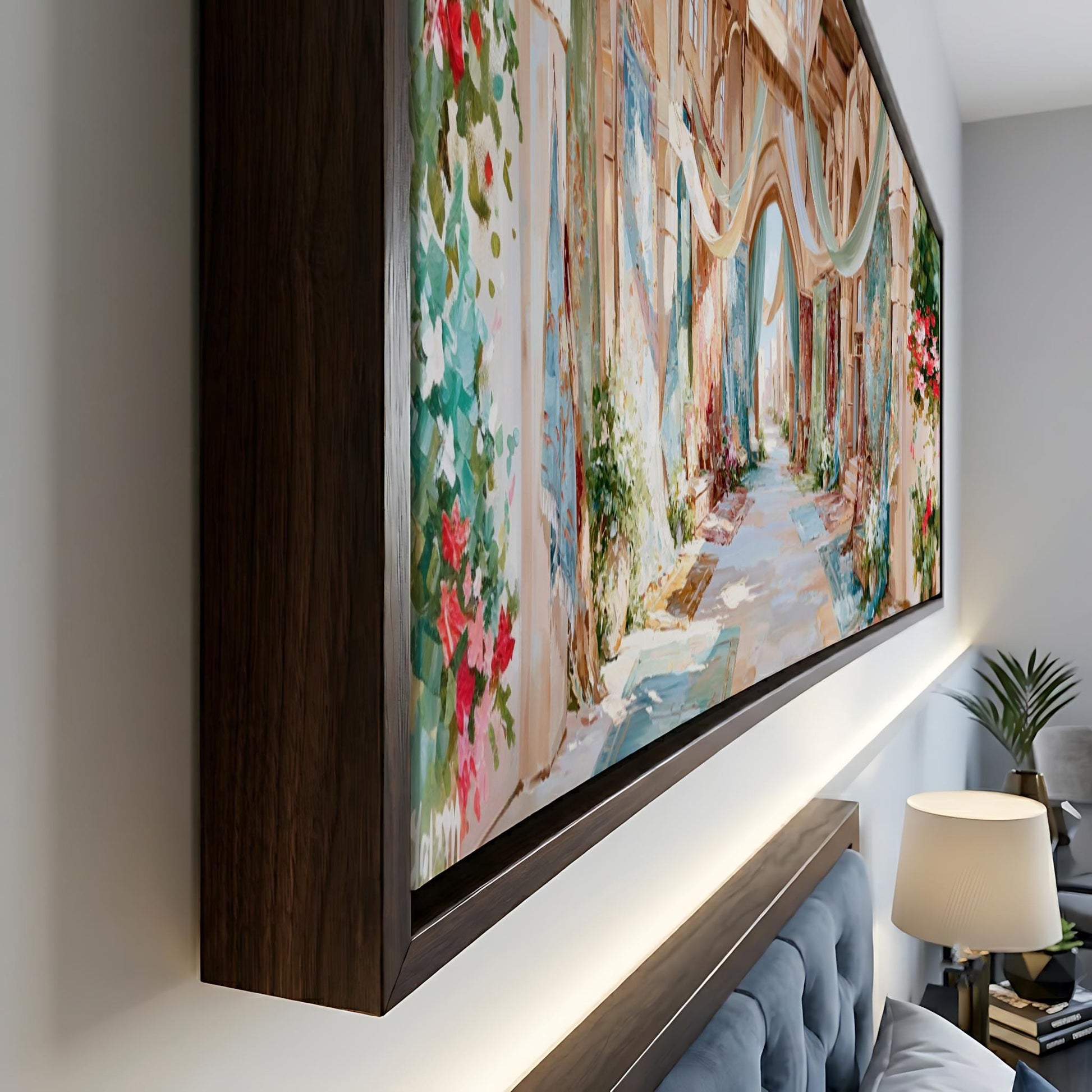 a large, colorful painting of a street scene with buildings, flowers, and a winding path. The painting is framed and displayed on a wall, creating a focal point in the room.