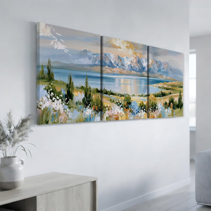 a large, three-panel landscape painting hanging on a white wall. The painting depicts a serene mountain range with a lake in the foreground, surrounded by lush vegetation and colorful flowers.
