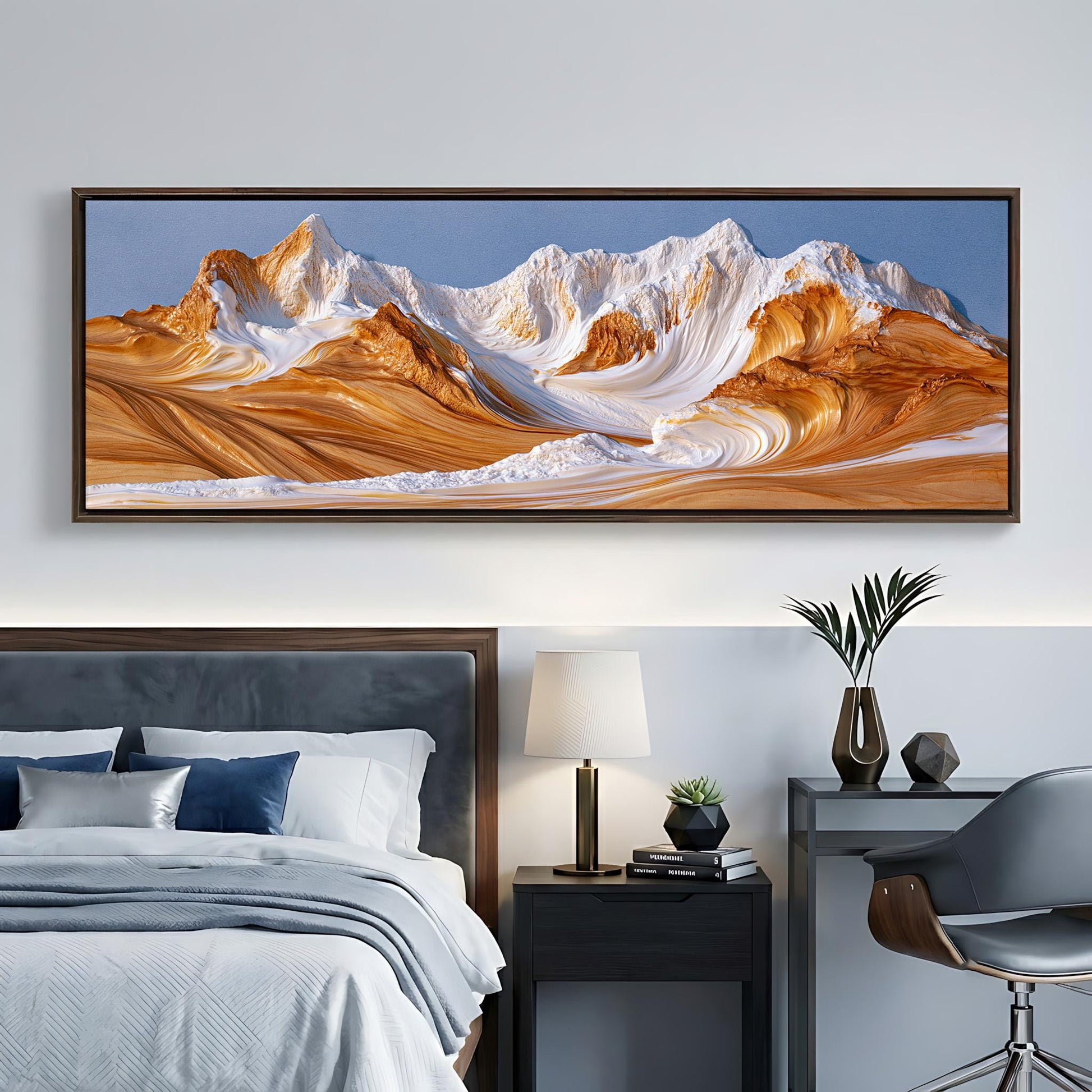 a large, framed landscape painting depicting a mountain range with a blue sky and orange and white peaks. The painting is hanging on a wall above a bed with a gray headboard.