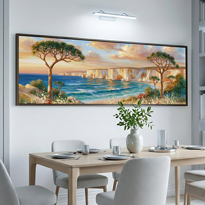 a large painting of a scenic landscape with a beach, trees, and a body of water, hanging on a wall above a dining table with chairs and place settings.