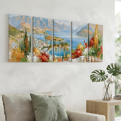 a large, colorful painting of a scenic landscape with mountains, a lake, and a town, hanging on a wall above a couch in a living room.