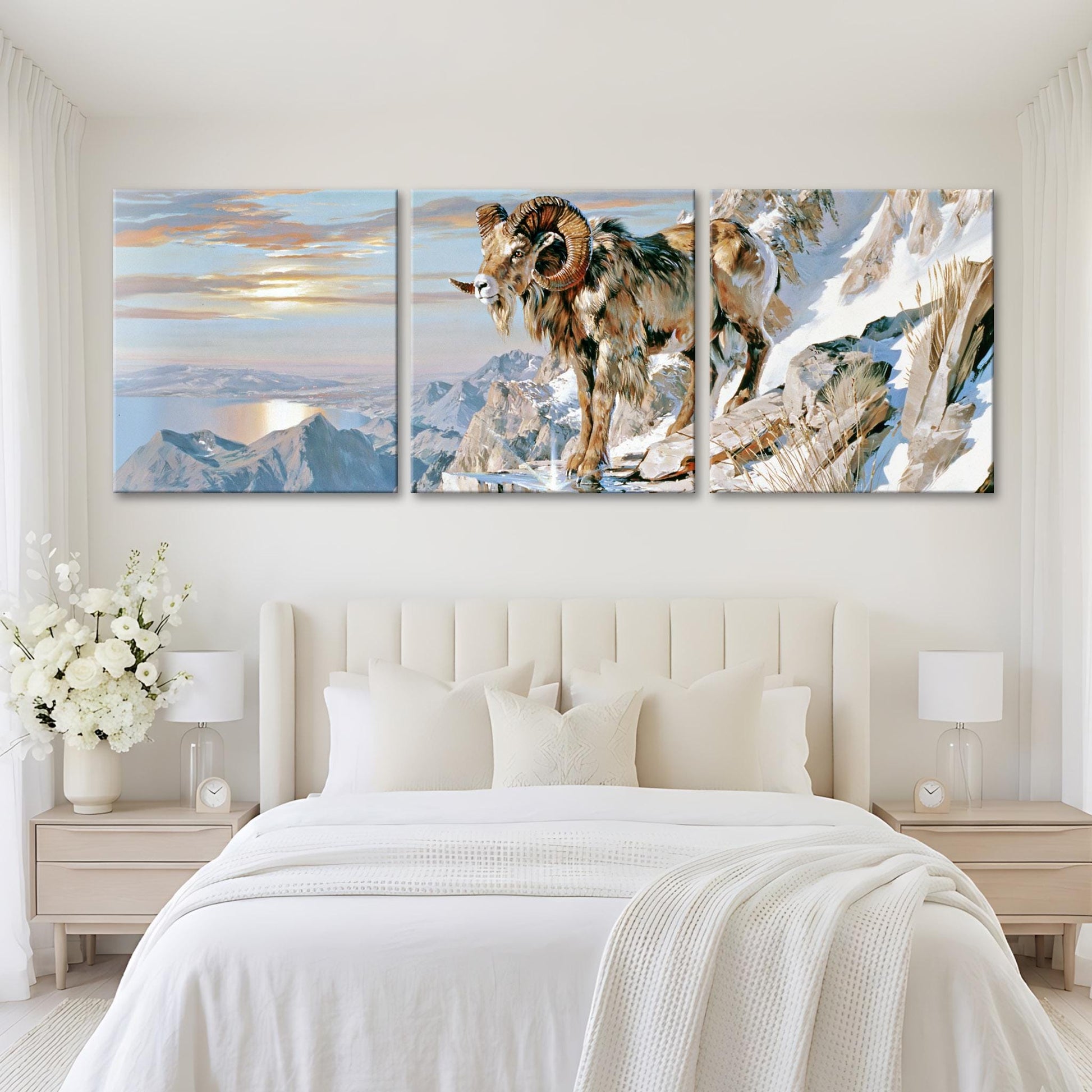 A bedroom with a large bed and two nightstands, each with a lamp. Above the bed are three large paintings depicting a mountain landscape with a ram in the foreground.
