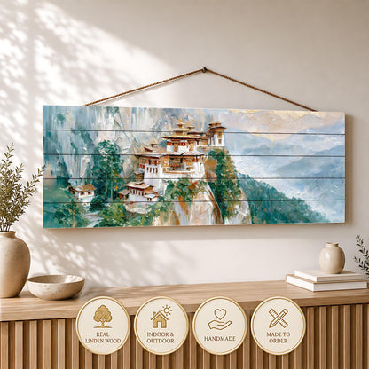 a wooden wall hanging depicting a picturesque mountain village with traditional architecture, surrounded by lush greenery.