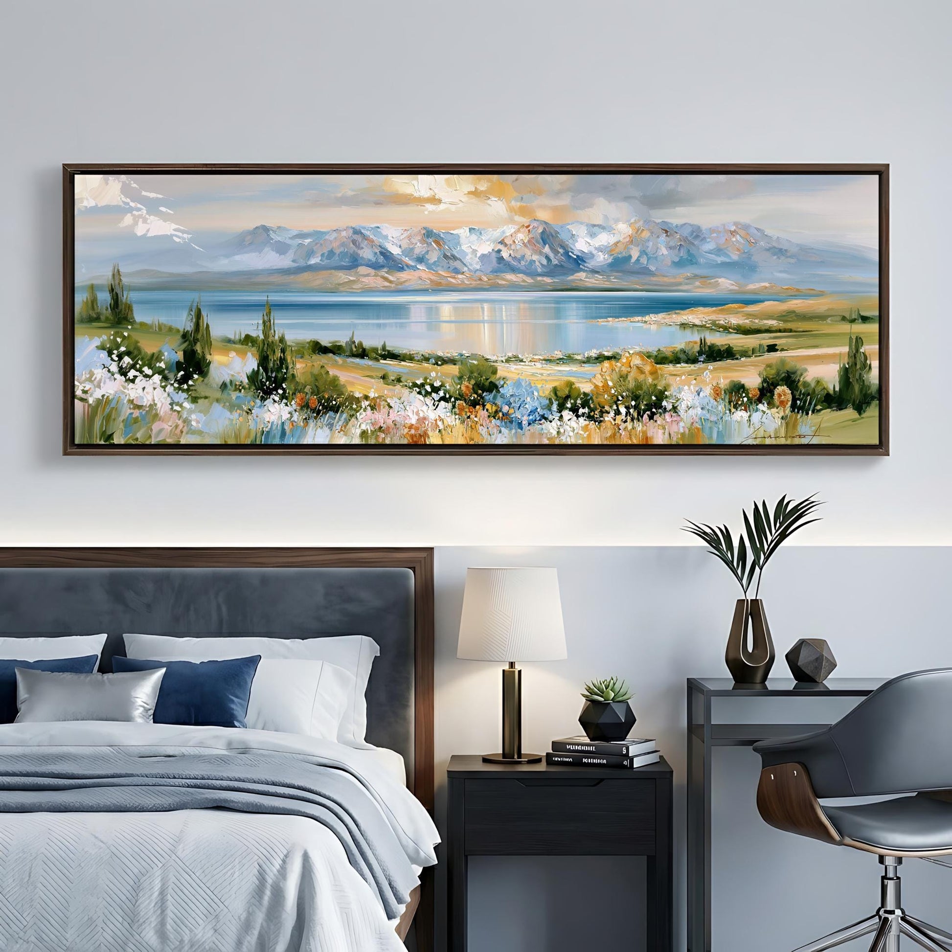 a serene bedroom scene with a large landscape painting hanging on the wall above a bed with a gray headboard. The painting features a picturesque mountain range and a tranquil lake, creating a peaceful and calming atmosphere.