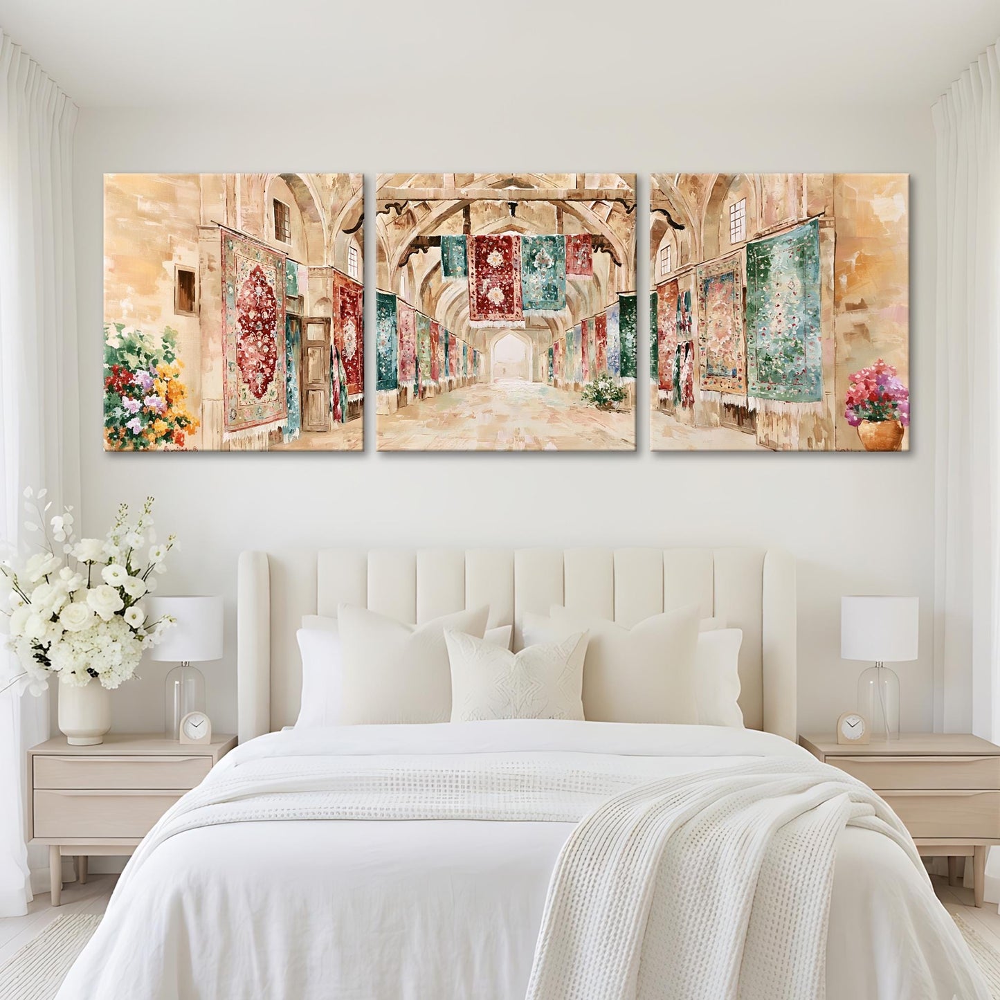 A large, three-panel painting depicting a hallway with arched doorways and colorful tapestries hanging on the walls. The painting is displayed on a white wall above a bed with white bedding and pillows.