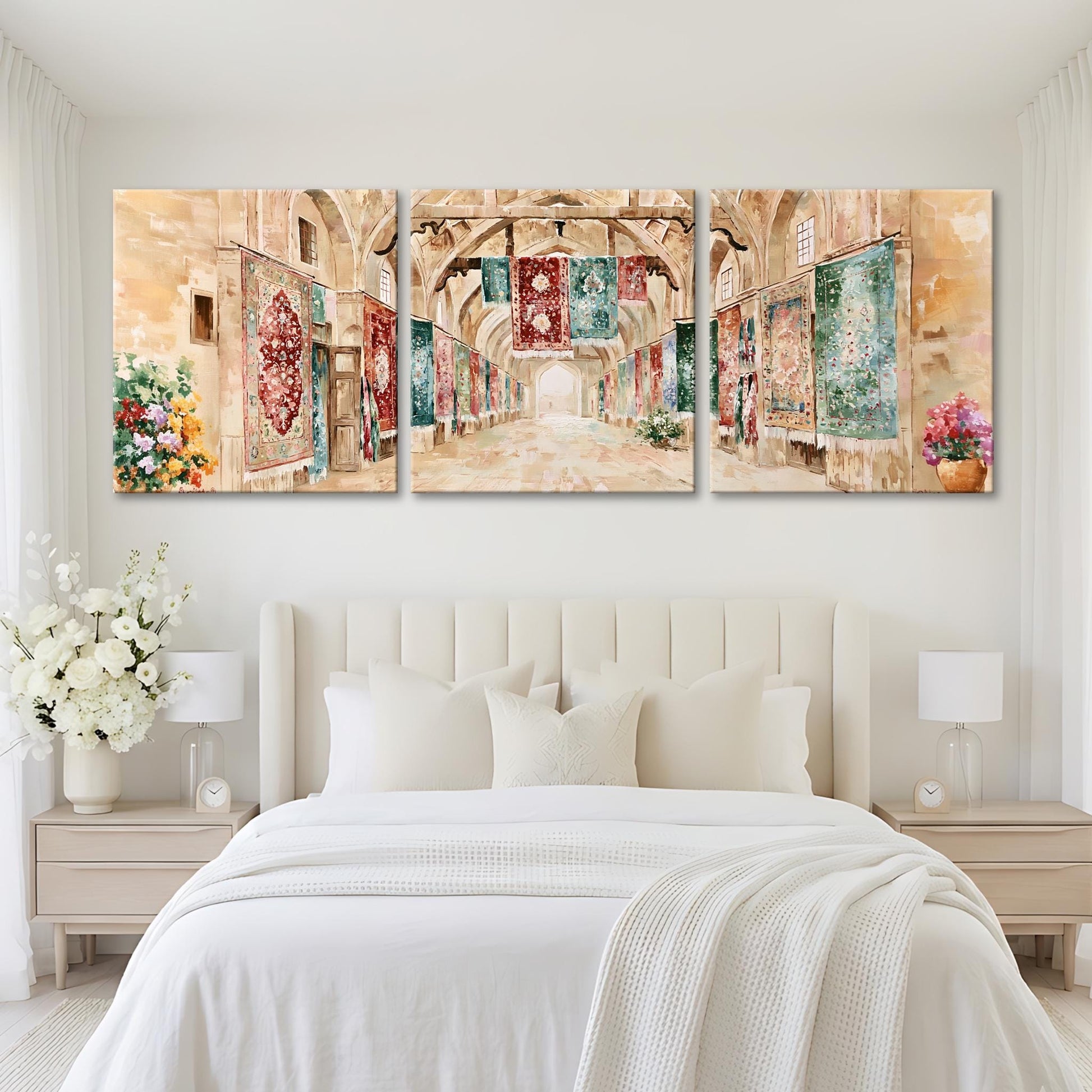 A large, three-panel painting depicting a hallway with arched doorways and colorful tapestries hanging on the walls. The painting is displayed on a white wall above a bed with white bedding and pillows.