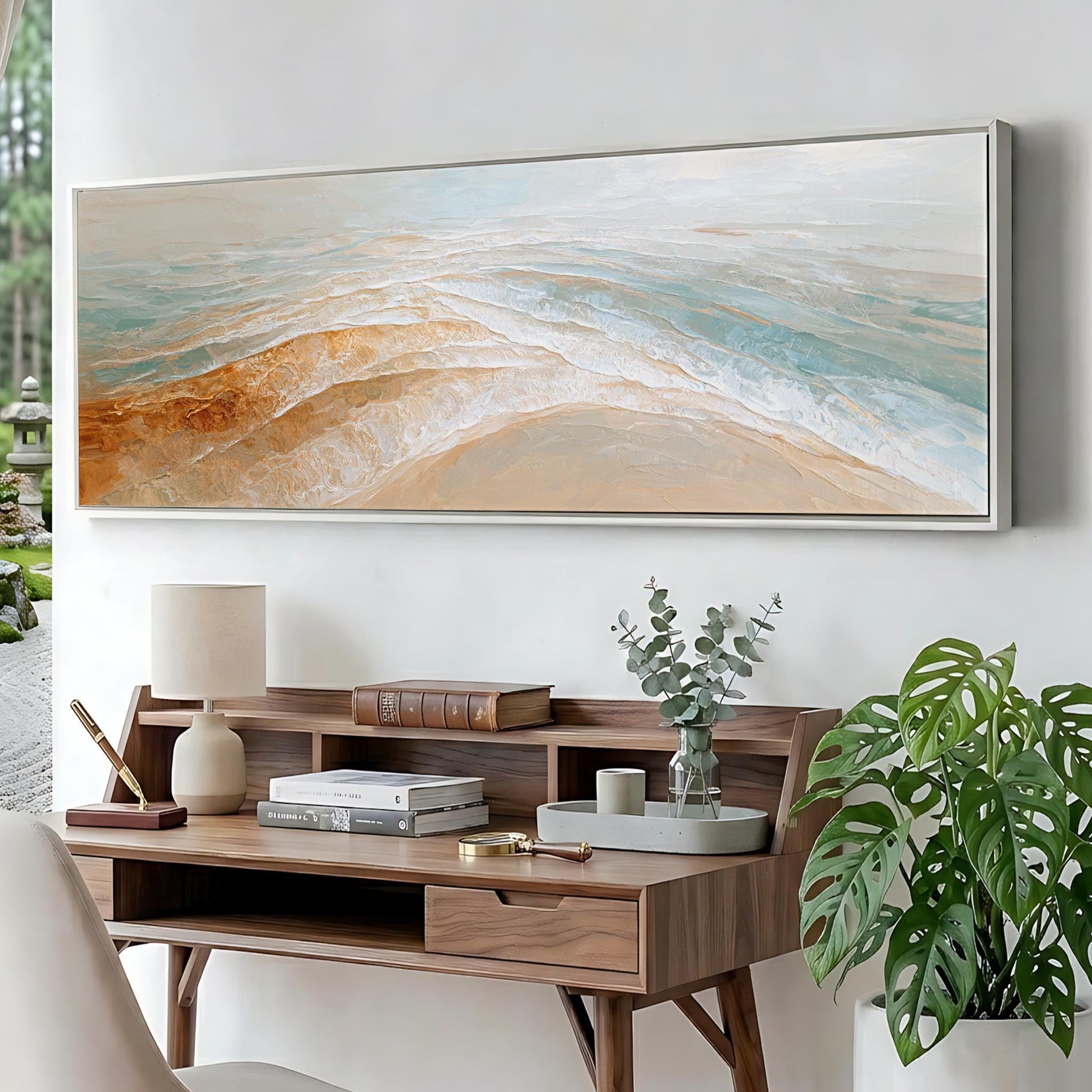 a wooden desk with a lamp, books, and a plant, set against a wall with a large painting hanging above it.