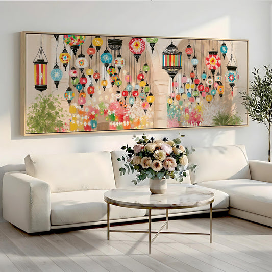 a large, colorful painting of hanging lanterns on a wall above a white sofa and a round coffee table with a vase of flowers.
