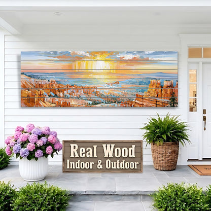 a large painting of a sunset over a cityscape, displayed on a white wall above a wooden sign that reads "Real Wood Indoor & Outdoor". The painting is surrounded by potted plants, and there is a door visible in the background.