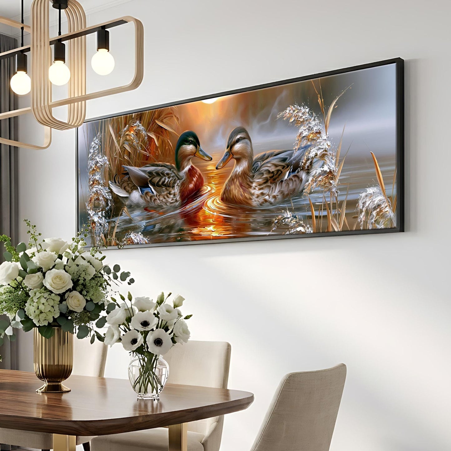 a large framed painting of ducks swimming in a pond, hanging on a wall above a dining table with a vase of flowers.