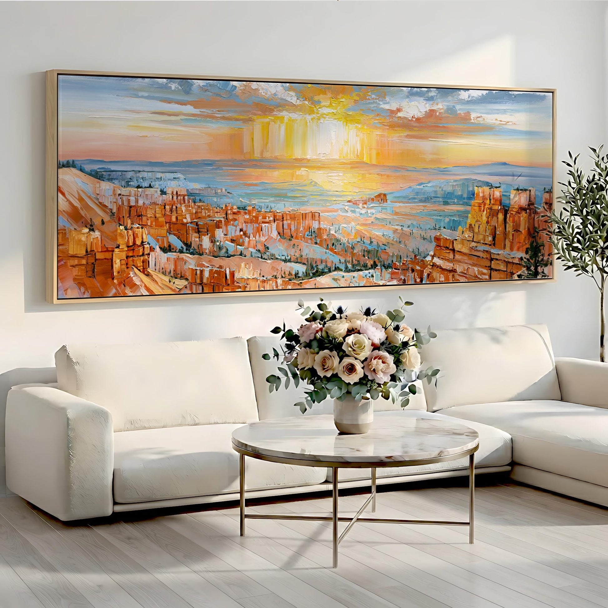 a large, colorful painting of a desert landscape hanging on a wall above a white sofa and a round coffee table with a vase of flowers.