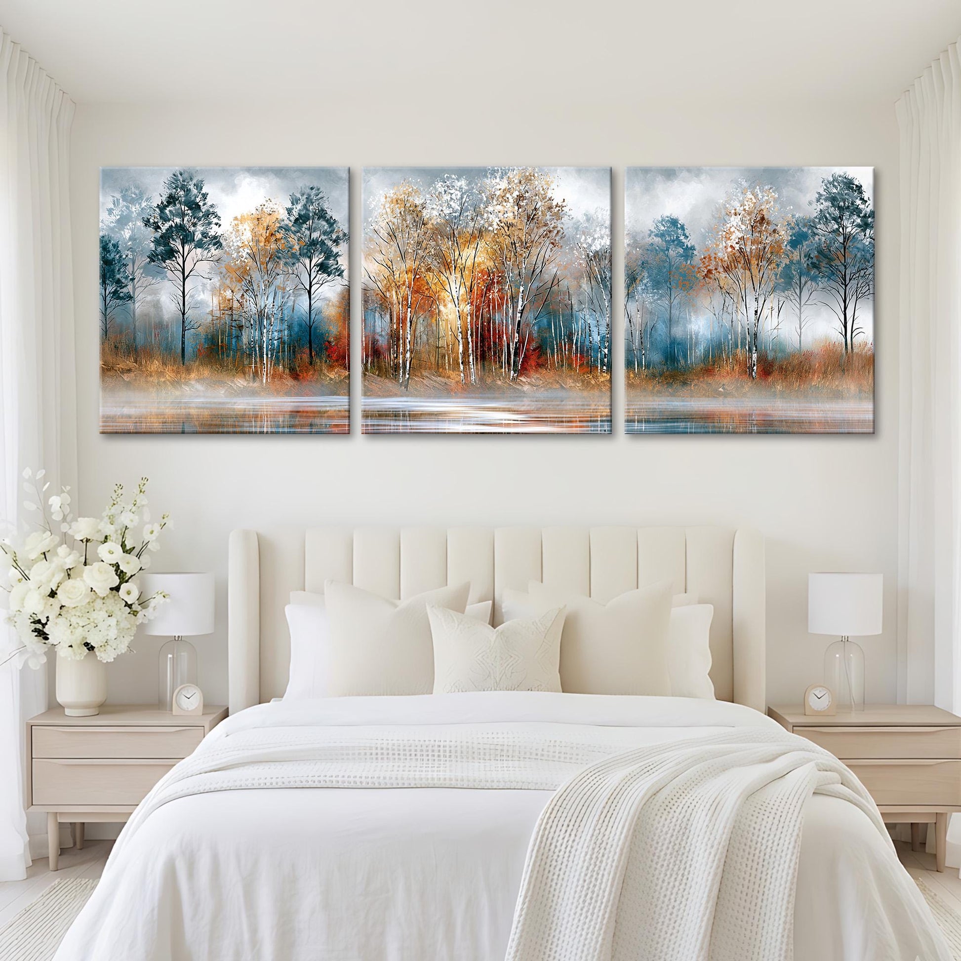 A modern bedroom with a large bed and white bedding. Above the bed are three large paintings depicting a serene landscape with trees and a body of water.