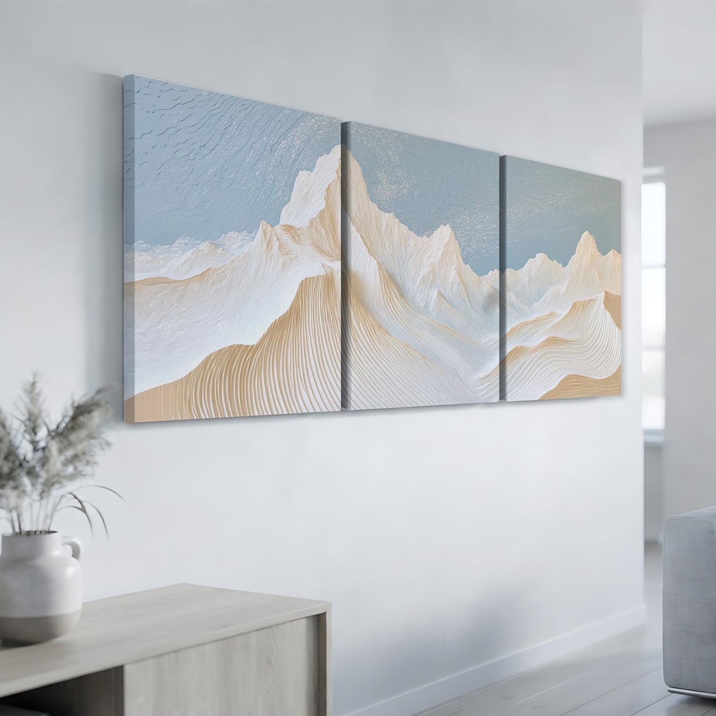 a modern art piece with three panels depicting a mountain landscape. The artwork is displayed on a white wall in a minimalist setting.