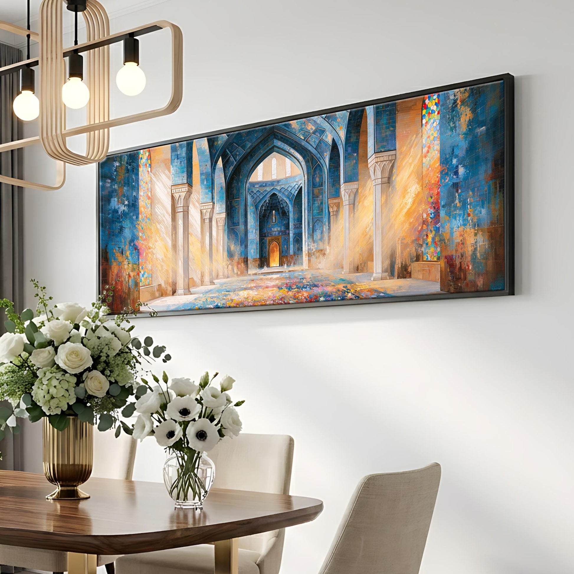 a large painting of an ornate, colorful archway with intricate details, hanging on a white wall above a wooden dining table with a vase of white flowers.