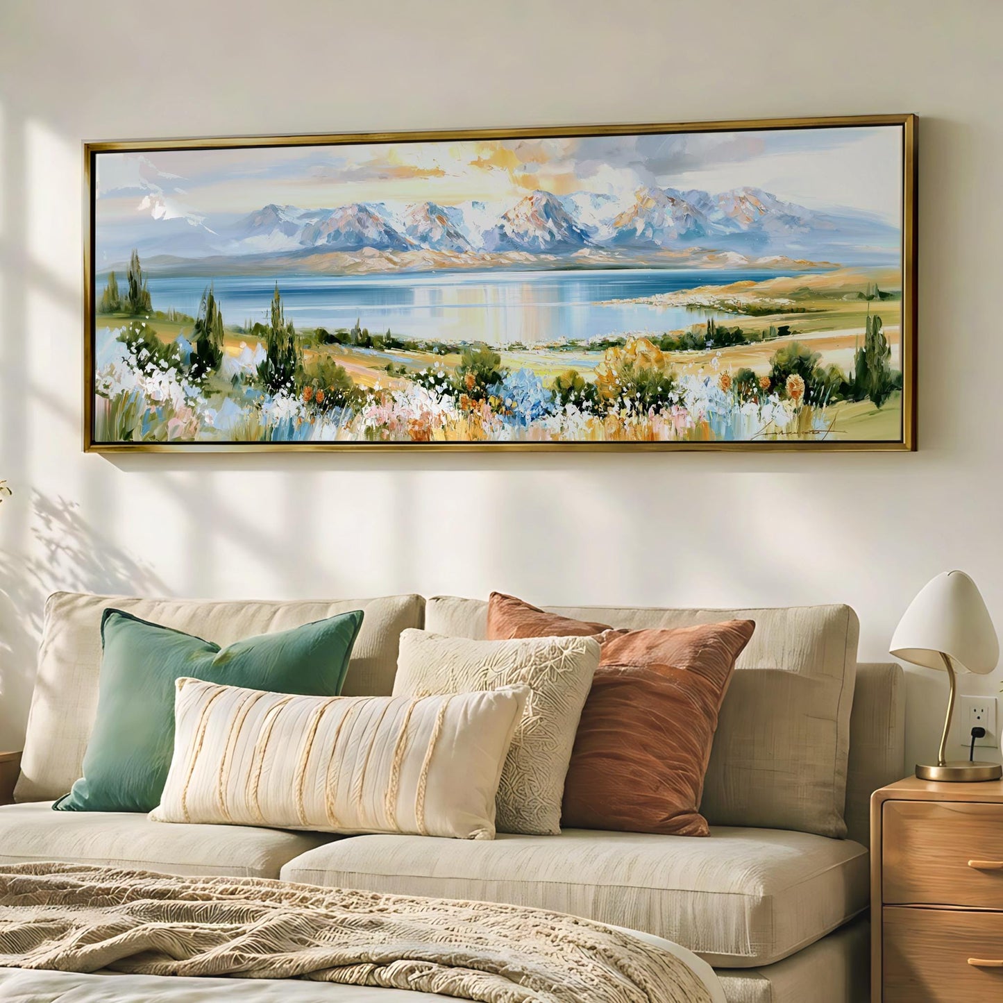 a large landscape painting hanging on a wall above a beige sofa with colorful throw pillows.
