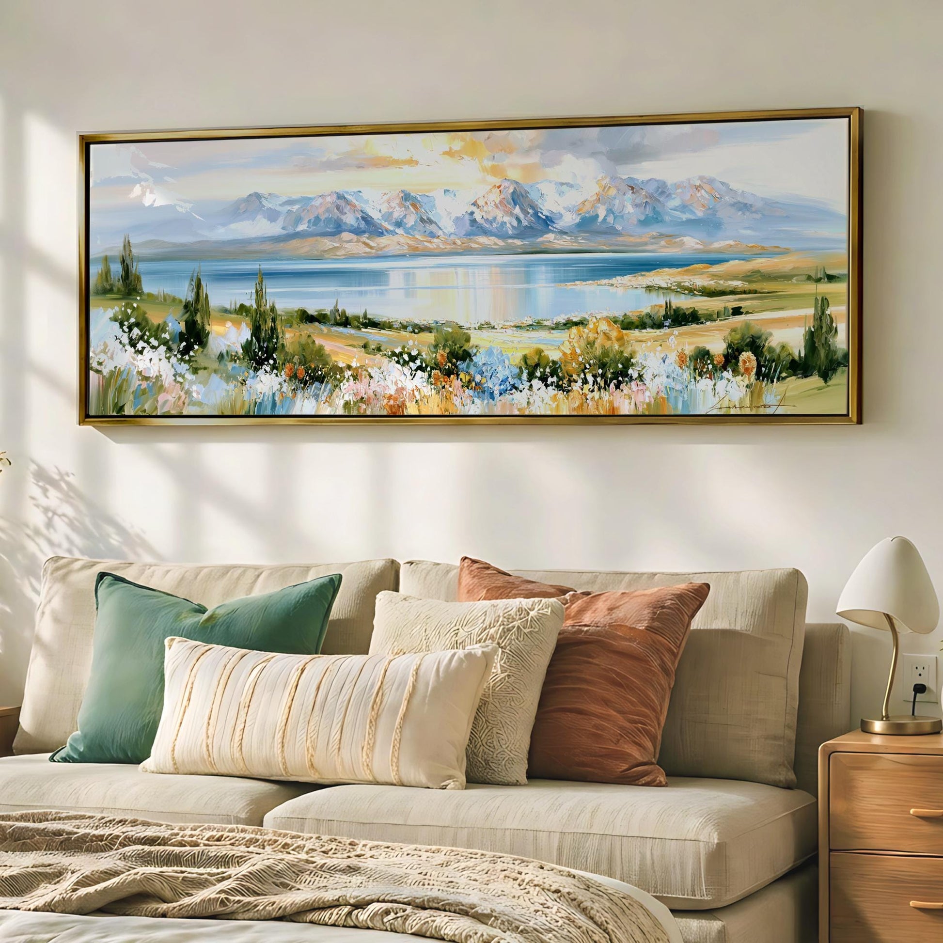 a large landscape painting hanging on a wall above a beige sofa with colorful throw pillows.