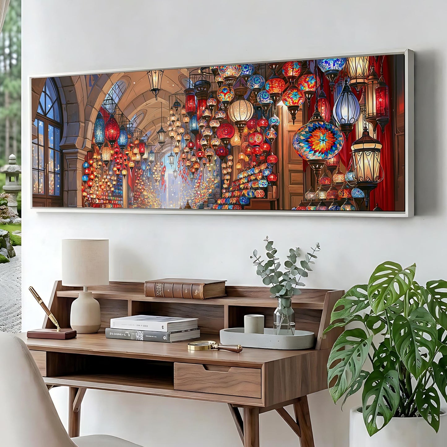 a large, colorful painting of a lantern-filled room hanging on a wall above a wooden desk with various items on it.