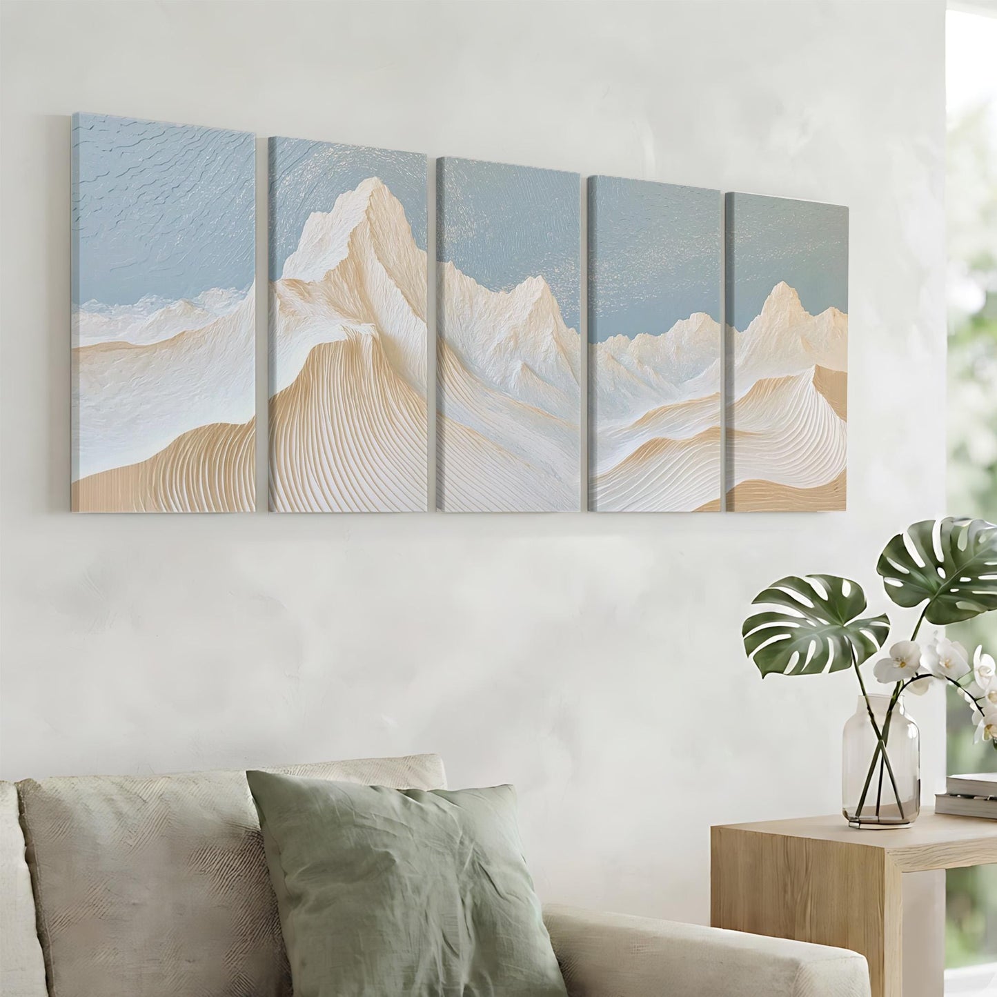 a living room with a large wall art piece depicting a mountain landscape with a blue sky and white clouds. The art piece is composed of five panels, each showcasing a different part of the mountain range. The room is furnished with a couch and a side table, creating a cozy and inviting atmosphere.