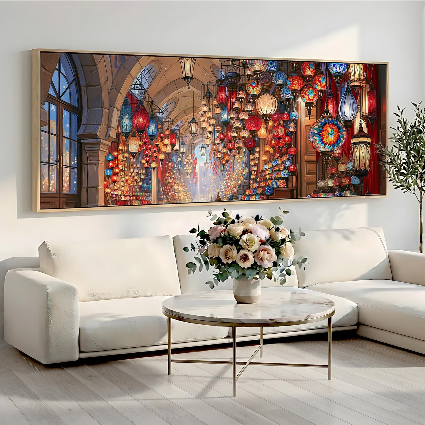 a large, colorful painting of a lantern-filled room hanging on a wall above a white sofa and a round coffee table with a vase of flowers.