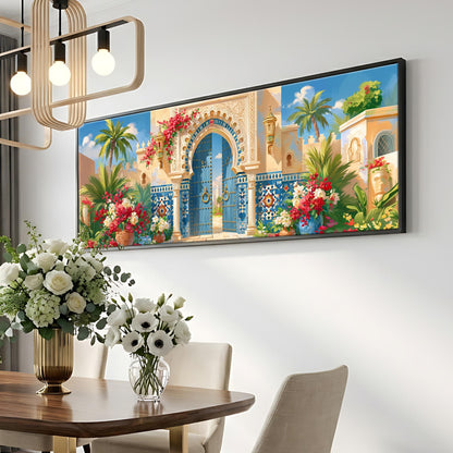 a large, colorful painting of an ornate, blue and yellow gate with a red archway, surrounded by tropical flowers and lush greenery. The painting is hung on a white wall above a wooden dining table with a vase of white flowers. The table is set with white chairs, and a chandelier hangs above the table, creating a warm and inviting atmosphere.