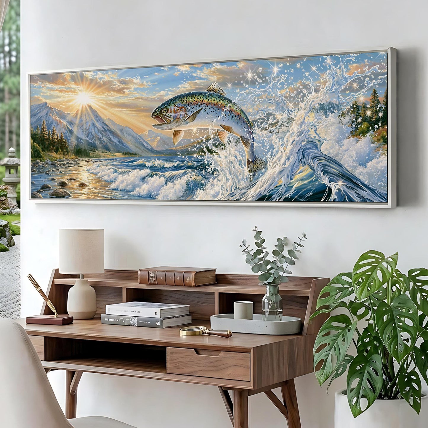 a large painting of a fish leaping out of the water, set against a backdrop of a mountain landscape with a sunset. The painting is hung on a wall above a wooden desk with various items on it, including a lamp, books, and a plant.