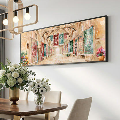 a dining room with a large painting of a hallway on the wall above a wooden table with a vase of white flowers. The painting is framed in black and hangs above the table. The dining table is set with a vase of white flowers, and there are two chairs visible in the room.