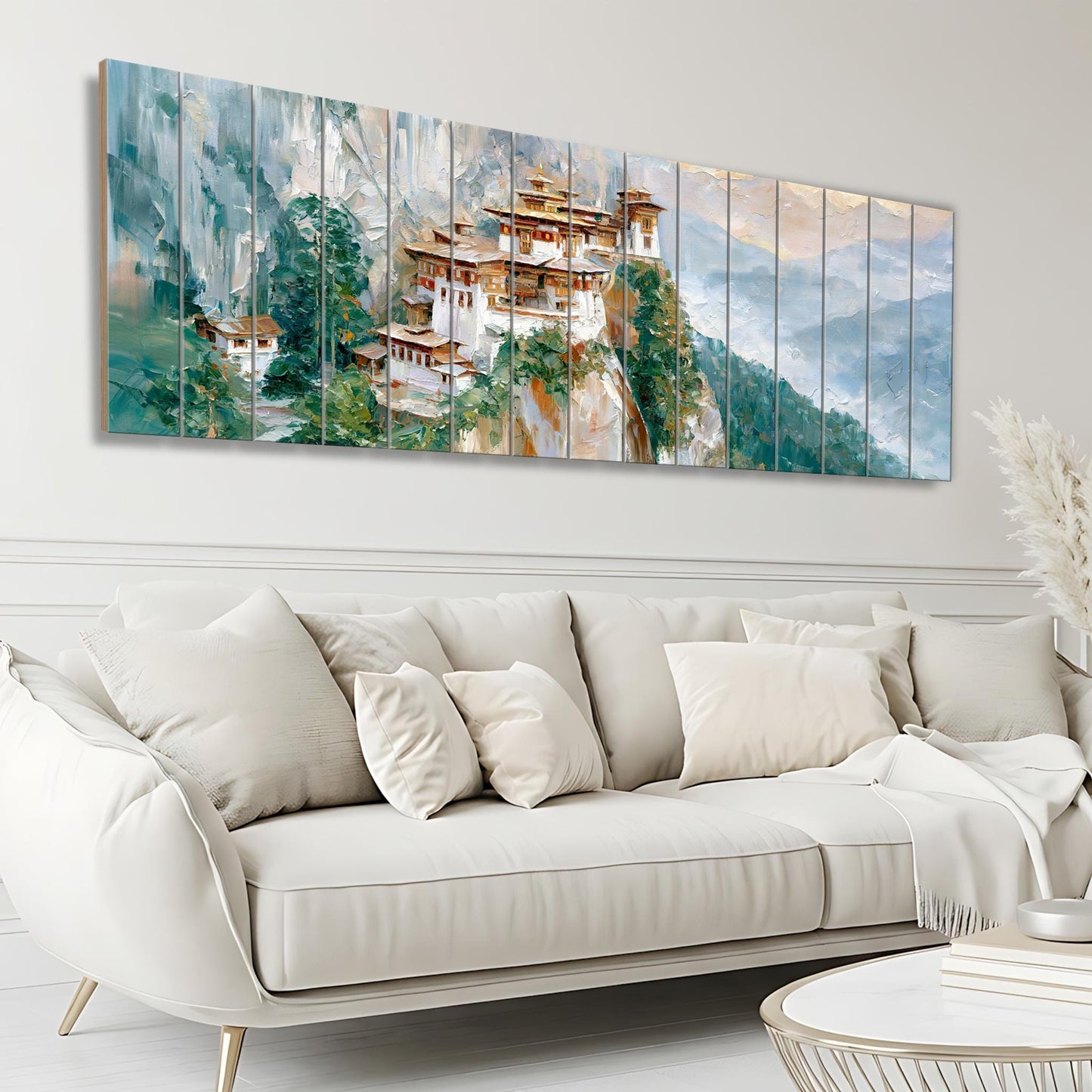 a large, colorful painting of a temple nestled in a mountainous landscape, hanging on a wall above a white sofa in a living room setting.