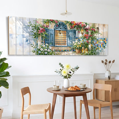 a dining area with a table set for two, featuring a vase of flowers, a plate of pastries, and two chairs. Above the table, there is a large painting depicting a window with a flower-filled sill.