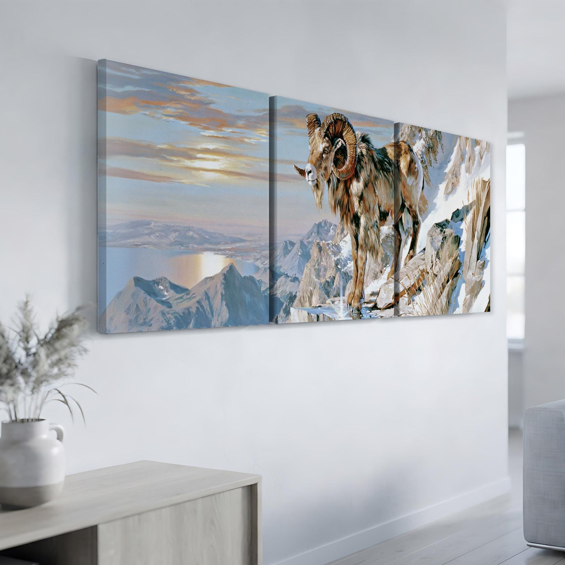 a large painting of a ram on a snowy mountain, hanging on a wall in a room with a vase of flowers on a table.