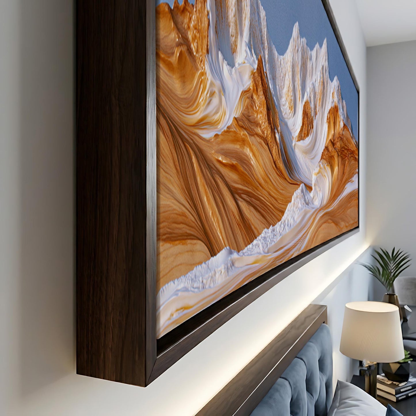 a large, framed painting of a mountain landscape with a warm, golden hue. The painting is displayed on a wall, and there is a lamp and a plant in the background, adding to the cozy atmosphere of the room.