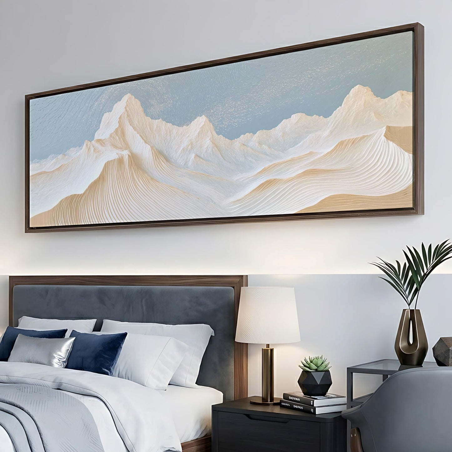 a large, framed painting of a mountain landscape hanging above a bed with a gray headboard.