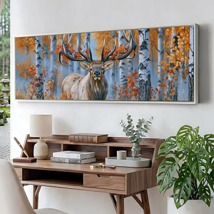 a large framed painting of a deer with antlers in a forest setting, hanging on a wall above a wooden desk with various items on it.