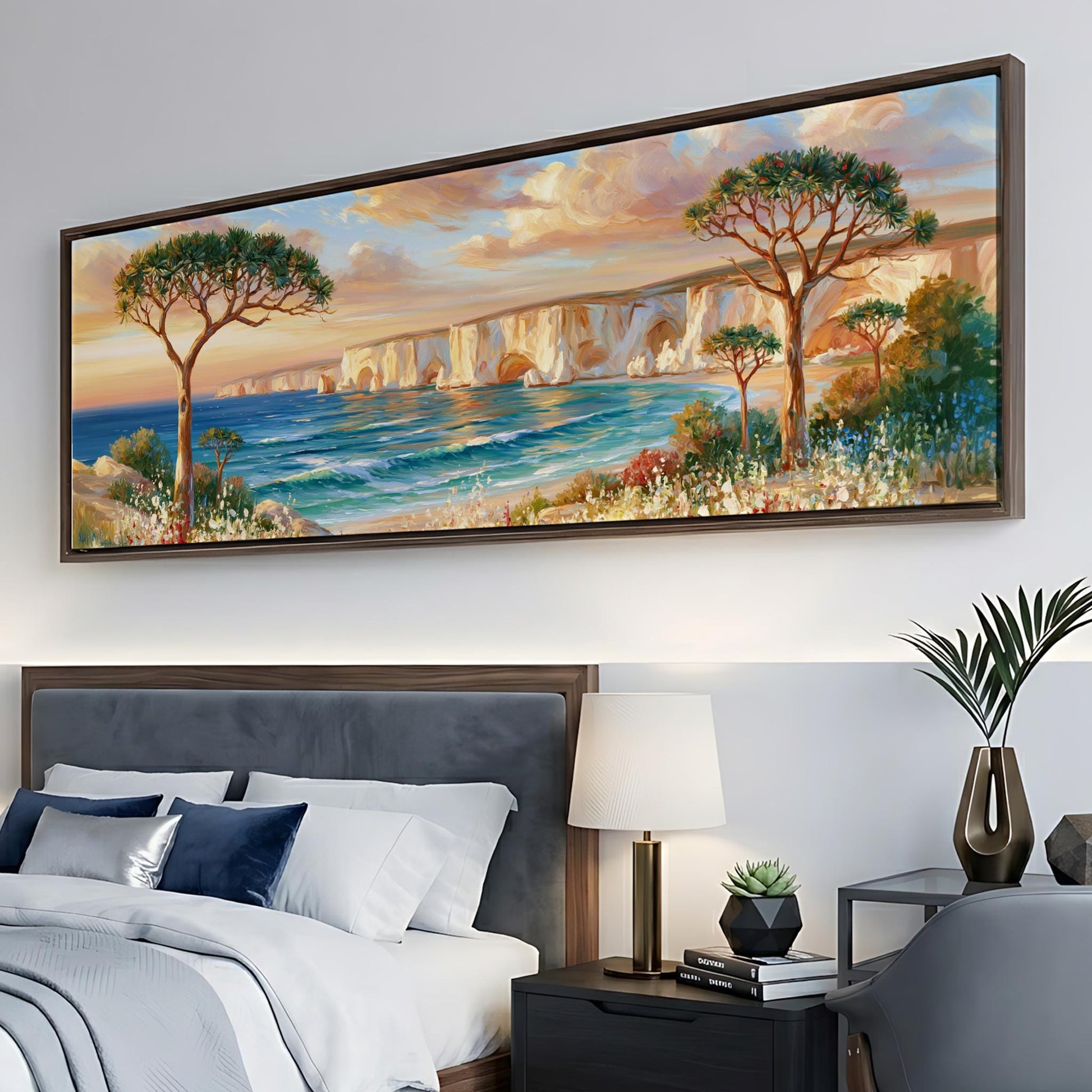 a large painting of a serene landscape with a cliff overlooking a body of water, surrounded by trees and flowers. The painting is hung on a wall above a bed with a gray headboard.