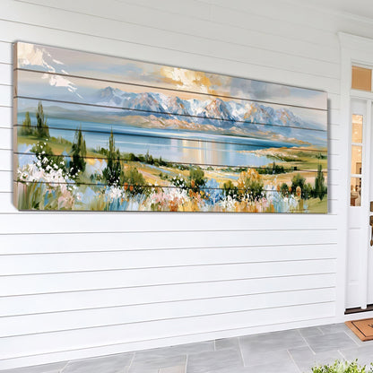 A large, colorful painting depicting a scenic landscape with mountains, a lake, and a field of flowers is displayed on the wall of a white house.