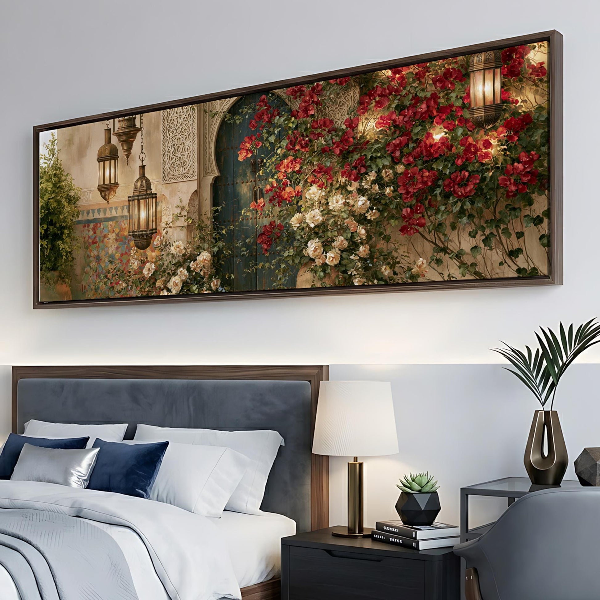 a large framed painting of a garden scene with red flowers and a green door, hanging above a bed with white linens and blue pillows.