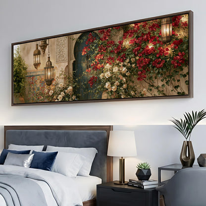 a large framed painting of a garden scene with red flowers and a green door, hanging above a bed with white linens and blue pillows.